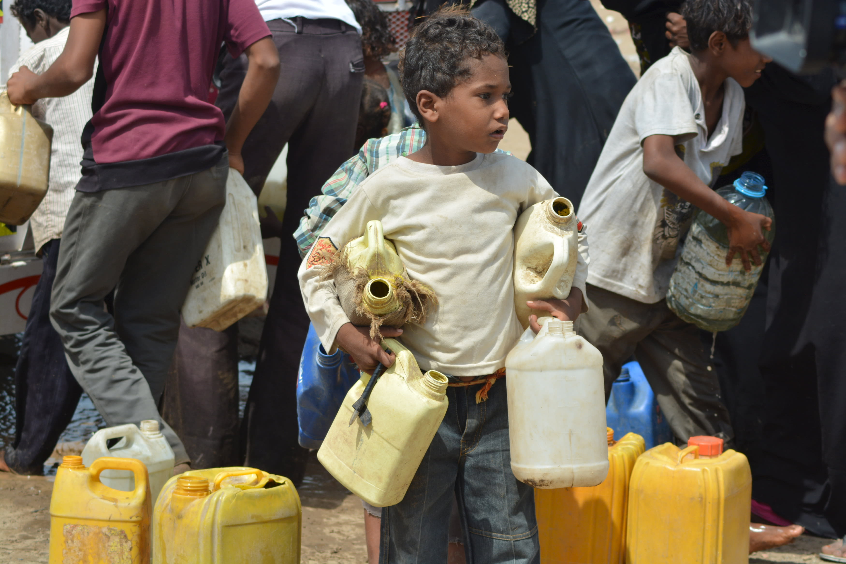 Boy carries jerry cans to fill from a water tanker truck in a slum neighborhood in Yemen's Red Sea city of Houdieda